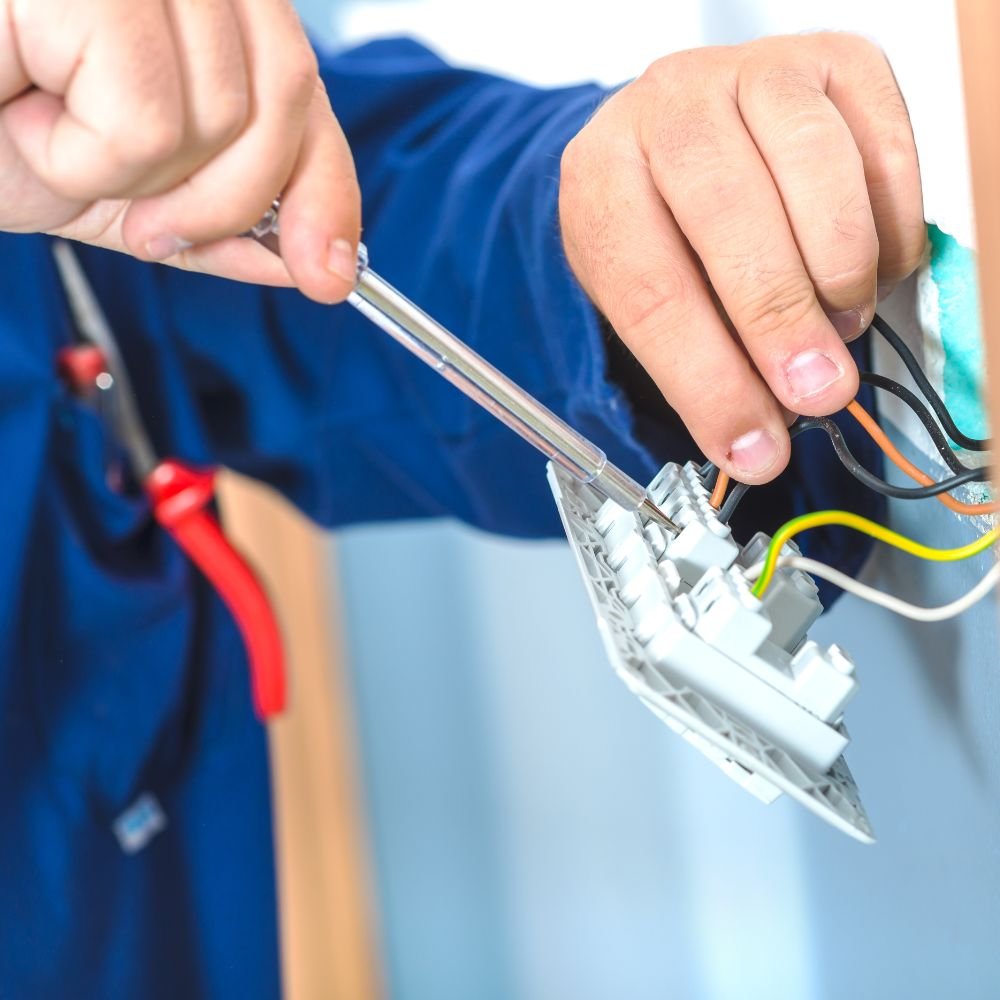 Electrician installing a power outlet, demonstrating residential electrical services and home repairs for upgrades in 2025.